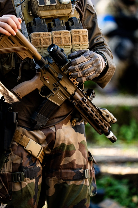 Powergun airsoft en main d'un joueur équipé chest rig pendant une partie