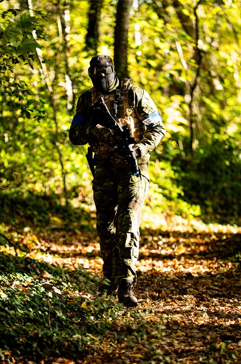 Joueur sniper airsoft camouflé en ghillie dans les bois d'un terrain airsoft