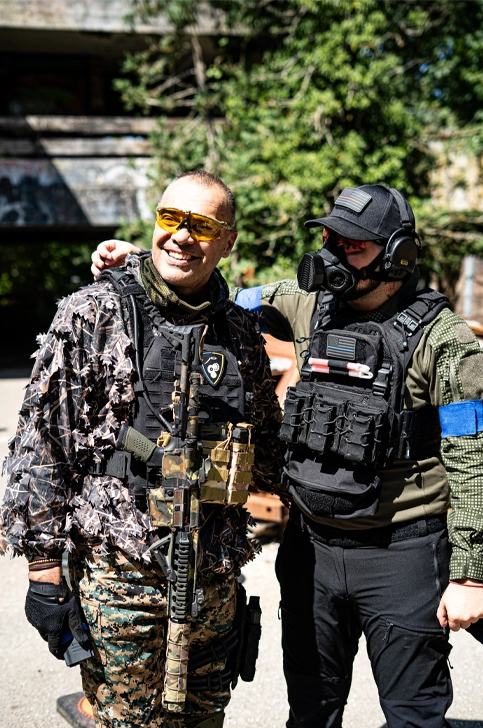 Duo de joueurs d'une team airsoft en tenue camo sur terrain extérieur